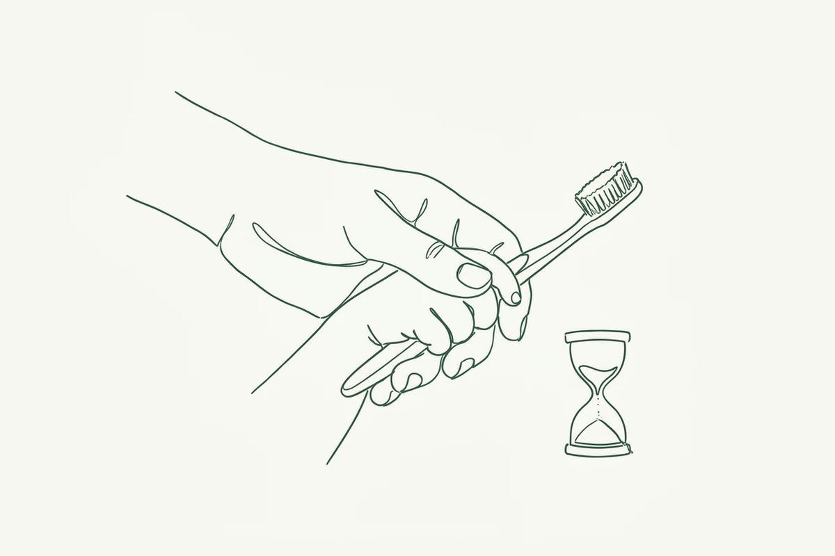 La mano di un genitore che guida quella del bambino sullo spazzolino